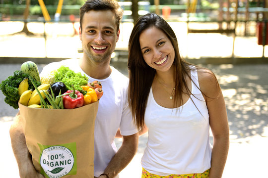 Happy couple carrying a bag of organic food.