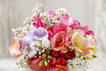 Bouquet of colorful freesia flowers in transparent glass vase.