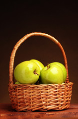 juicy green apples in basket on wooden table on brown