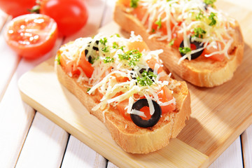 Delicious bruschetta with tomatoes on cutting board close-up