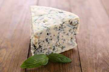 Tasty blue cheese with basil, on wooden table