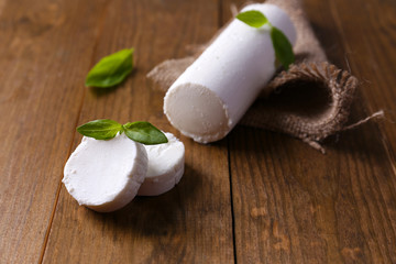 Tasty bushe cheese with basil, on wooden table