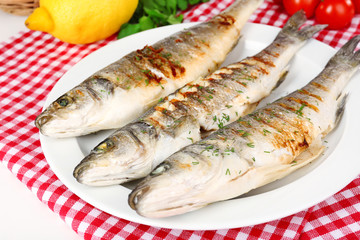 Delicious grilled fish on plate on table close-up