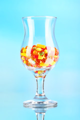 Goblet with pills on blue background