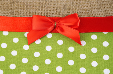 Sackcloth with color ribbon and bow on color fabric background