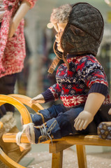 Young kid mannequins in winter hats and sweaters under shopping