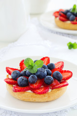 Sand tartlet with vanilla cream, strawberries and blueberries.