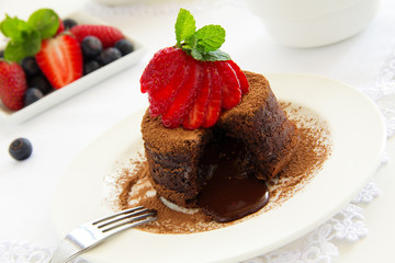 Chocolate dessert fondant with a liquid center and strawberries.