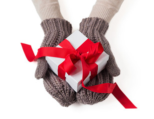 Present in white box with red ribbon in warm wool gloves