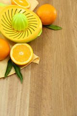 Citrus press and oranges on wooden background