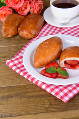 Fresh baked pasties with strawberries on plate on table