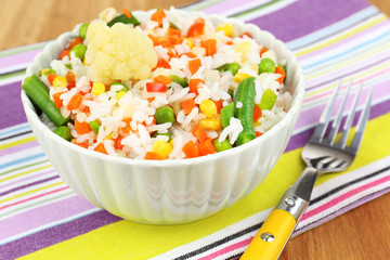 Cooked rice with vegetables on wooden table close up