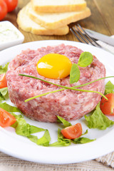 Delicious steak tartare with yolk on plate on table close-up