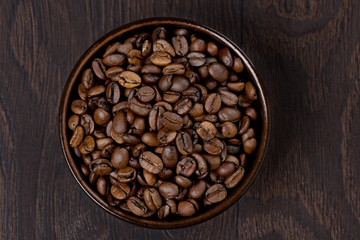 bowl of coffee beans on a dark background, top view