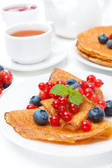 Breakfast with pancakes, fresh berries and black tea on white