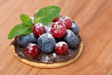 cake with chocolate cream, berries on wooden background