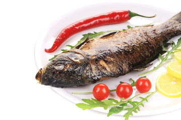 Grilled carp with vegetables on plate.