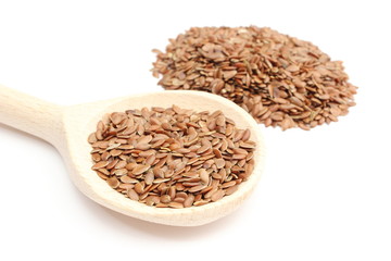 Heap of linseed with wooden spoon on white background