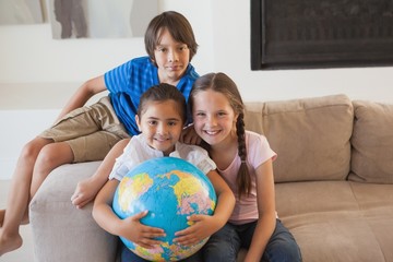 Fototapeta premium Portrait of happy kids with globe in living room