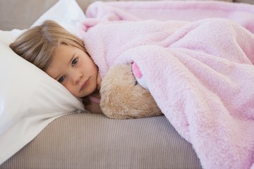 Young girl resting on sofa with stuffed toy