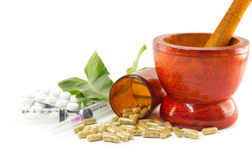 Mortar and pestle with herb capsules spilling out of bottle