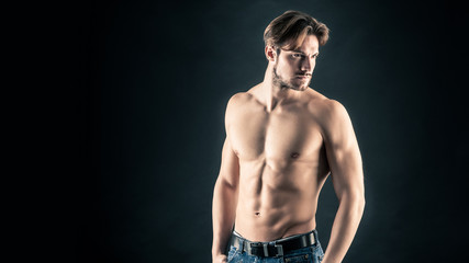 Portrait of confident young man shirtless against black backgrou
