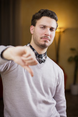 Disappointed or displeased young man doing thumb down sign