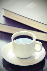 Coffee break at work. Coffee cup on a pile of books.