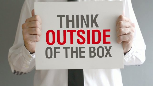 Businessman holding paper with Think Outside of the Box title.