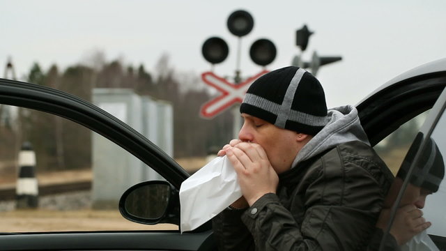 orried man breathe into a paper bag near rail crossing