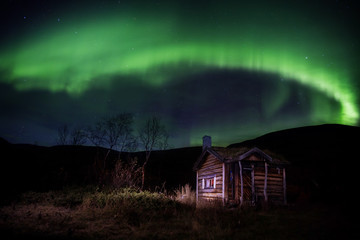 wooden cabin under northern lights