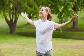 Smiling woman with arms outstretched at park