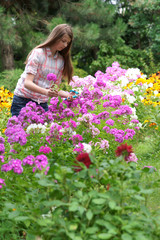 Fototapeta na wymiar Girl cuts flowers in the garden