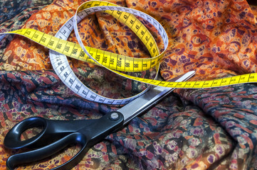 Tailor measuring tape and scissors on patterned fabric