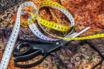 Tailor measuring tape and scissors on patterned fabric
