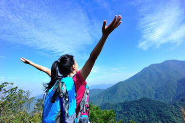 cheering woman hiker open arms at mountain peak