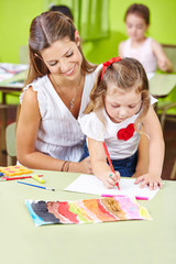 Tagesmutter malt mit Kindern