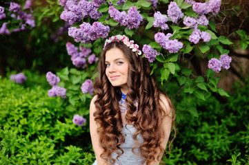 Naklejka premium Beautiful young woman in lilac flowers, outdoors portrait