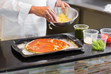 Mid section of a chef garnishing food in kitchen