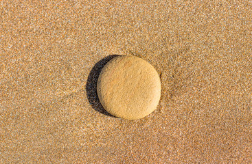 Round stone in the wet sand