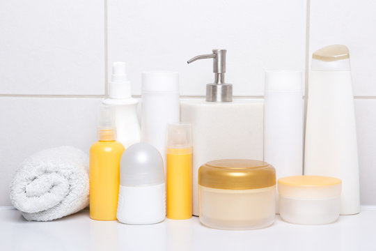 Set Of White And Orange Cosmetic Bottles Over Tiled Wall