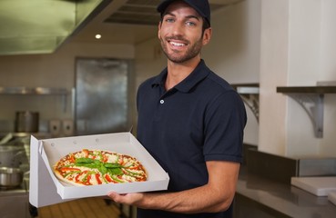 Happy pizza delivery man showing fresh pizza