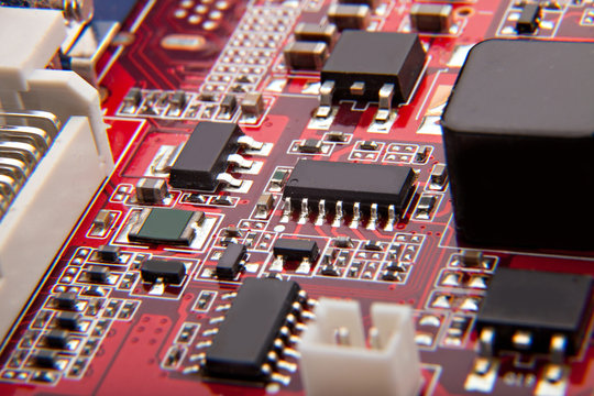 red electronic microcircuit with microchips and capacitors