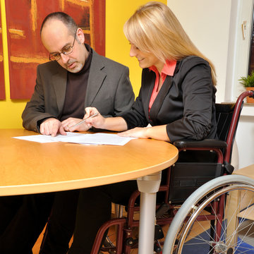 Frau mit Rollstuhl bei Besprechnung im Büro