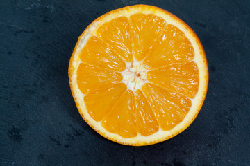 Orange coupée en deux sur fond d'ardoise
