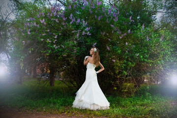 Obraz na płótnie Canvas Beautiful bride in a white dress on a lilac background in spring