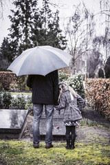 widower with daughter visiting graveyard