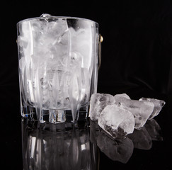 Ice and ice bucket over black background