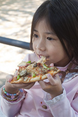 Little Asian girl enjoy eating pizza.