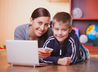 mom and son are lying on wood floor with laptop